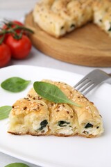 Piece of delicious puff pastry with spinach on table, closeup