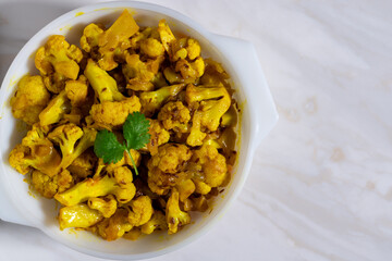 Spicy cauliflower vegetable curry dish cooked Indian cuisine served in dish on marble background. Top view. Copy space.