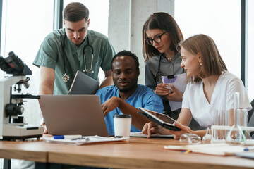 Reading information from laptop. Group of doctors are together indoors