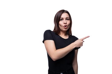 Caucasian cute young woman with black hair dressed in a black t-shirt gesturing on a white background with copy space