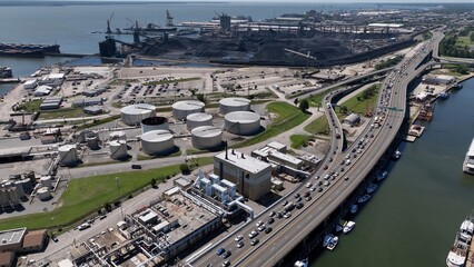Shipyard beside interstate highway with cars traveling past coal refinery and boats in harbor 