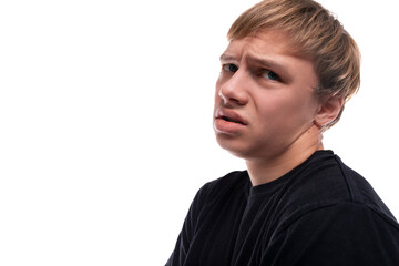 Upset fair-haired teenager guy in a black T-shirt on a white background
