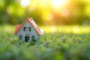 home model and life concept on green grass with sunlight