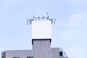 Steel color white large billboard located on roof of building Blue sky background with bright sunlight. Industrial, business concept. large outdoor advertising billing board.