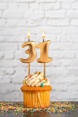 Cupcake with number 31 birthday candle - White block wall background
