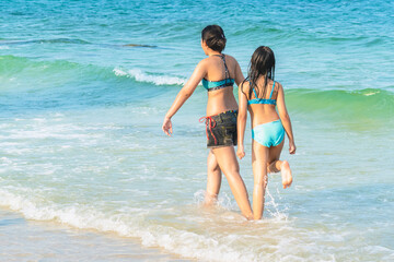 Mother and teenage daughter playing together on tropical beach at daytime. Mom and lovely daughter enjoy and fun outdoor lifestyle on beach. Happy family outdoors vacation. Friendly family Concept.