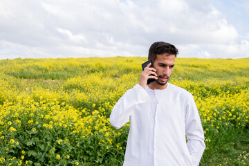 young arabic male making phone call during vacation in park, working from anywhere and stay...
