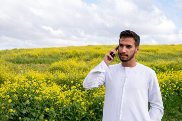 young arabic male making phone call during vacation in park, working from anywhere and stay...