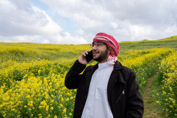 young arabic male making phone call during vacation in park, working from anywhere and stay...