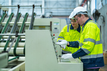 Male and female engineers in neat work clothes prepare and control the production system of large...