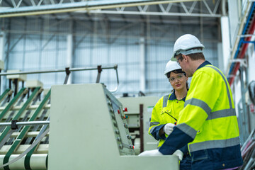 Fototapeta na wymiar Male and female engineers in neat work clothes prepare and control the production system of large modern machines in a factory producing industrial technology products.