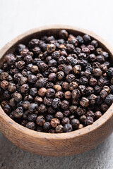 Indian spice black pepper in wooden bowl close-up on gray background