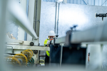 male engineers in neat work clothes prepare and control the production system of large modern machines in a factory producing industrial technology products.