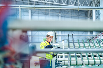 Male and female engineers in neat work clothes prepare and control the production system of large modern machines in a factory producing industrial technology products.