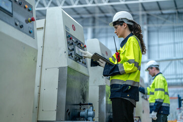 Male and female engineers in neat work clothes prepare and control the production system of large modern machines in a factory producing industrial technology products.