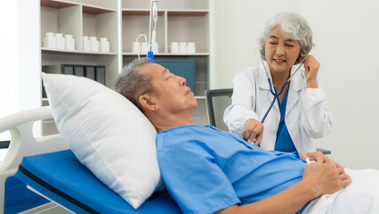 Obraz premium Senior Asian male patient visits the doctor for his annual checkup. Caregivers in caring for the elderly provide assistance on the bed Hospitals and Medicine and Health Care and Life Insurance