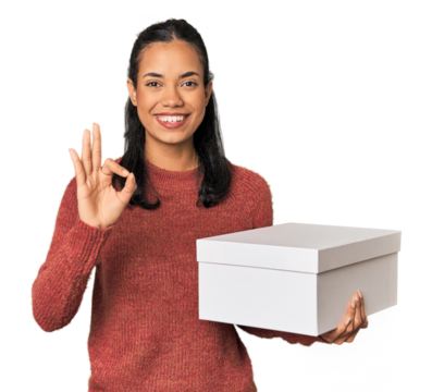 Young Filipina holding a box cheerful and confident showing ok gesture.