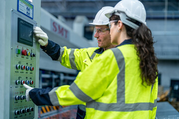 Male and female engineers in neat work clothes prepare and control the production system of large...