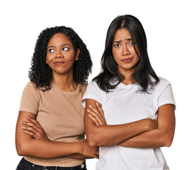 Young Latin friends in studio suspicious, uncertain, examining you.
