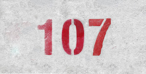Red Number 107 on the white wall. Spray paint.