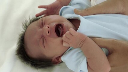 Newborn baby crying, capturing the challenges and realities of early parenthood. Highlights of patience, tenderness, nurturing during the early stages of child's life. Perfect for parenting resources