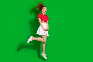 Full length photo of lovely young lady charming jumping dressed stylish red retro garment isolated on green color background