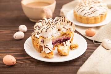 Tartlets with meringue cream and cup of coffee on brown wooden, side view, selective focus.