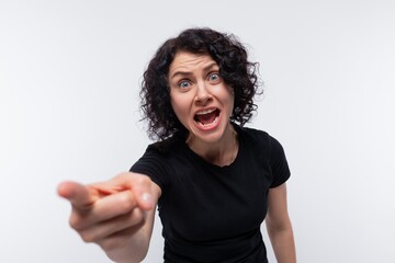 An angry brunette with curly hair dressed in a black T-shirt is indignant and screams