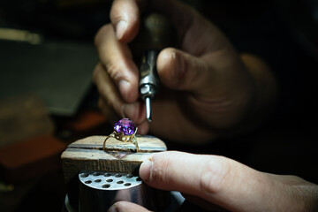 Close up of a goldsmith's hand making a gold or silver ring or a diamond using goldsmith's tools....