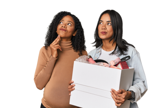 Latin women couple moving, one pregnant  looking sideways with doubtful and skeptical expression.