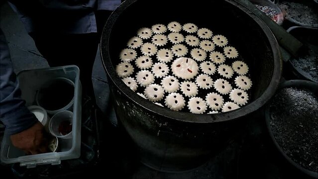 Footage of Baker Adding Dried Winter Melon on the Mid-baked Batter of Portuguese-Siamese Kudeejeen Cupcakes in a Brazier