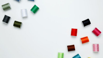Multicolored sewing threads on white background. Top view, copy space