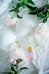 Valentine's Day. Bouquet of pink peonies, women's things, lace underwear, cosmetics on the bed. Spring mood.