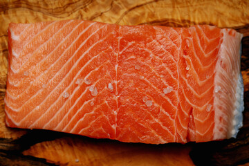 Raw salmon on olive tree cutting board