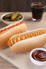 Tasty hot dogs with mustard and ketchup on wooden table