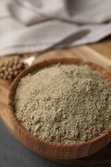 Aromatic spice. Ground pepper in bowl and peppercorns on grey wooden table, closeup