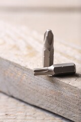 Different screwdriver bits on wooden table, closeup