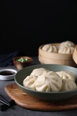 Delicious bao buns (baozi) in bowl on grey table, closeup