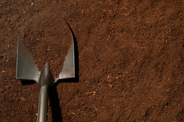 Metal shovel on fertile soil, top view and space for text. Gardening tool