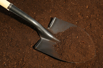 Metal shovel on fertile soil. Gardening tool