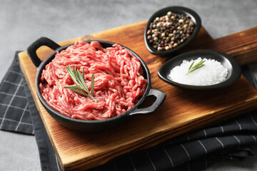 Raw ground meat in bowl and spices on grey table