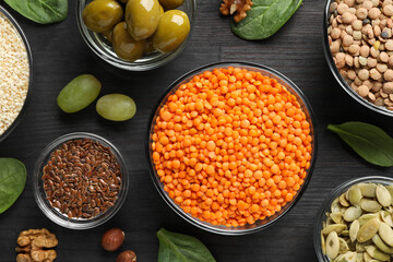 Different products high in healthy fats on black wooden table, flat lay
