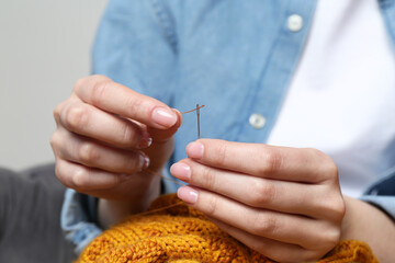 Woman inserting thread through eye of needle, closeup