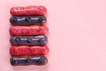 Delicious eclairs covered with glaze on pink background, top view. Space for text