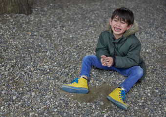 latino child sitting on the floor crying, whimpering in a public park. Concept of managing emotions...