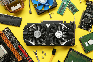 Graphics card and other computer hardware on yellow background, flat lay