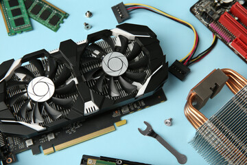 Graphics card and other computer hardware on light blue background, above view