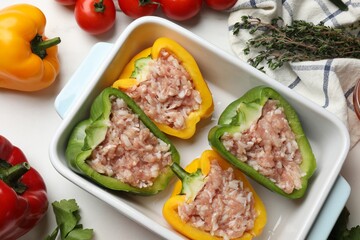 Raw stuffed peppers and ingredients on white table, flat lay