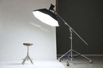 White photo background, stool and professional lighting equipment in modern studio