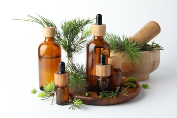Aromatherapy. Different essential oils, fir twigs, mortar and pestle on white background